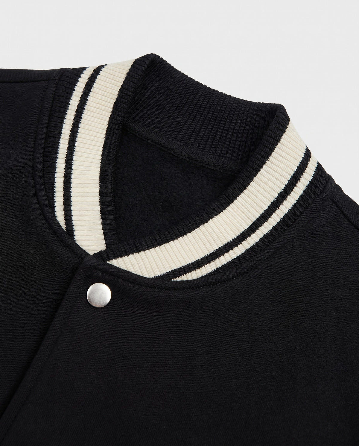 Détail du col rayé de la varsity jacket noire