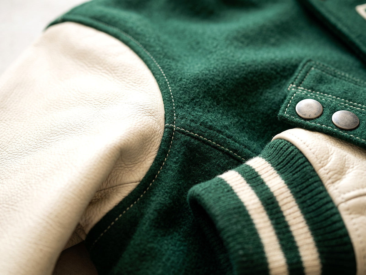 Détail des finitions d’une veste teddy : coutures, boutons pression et poignet rayé