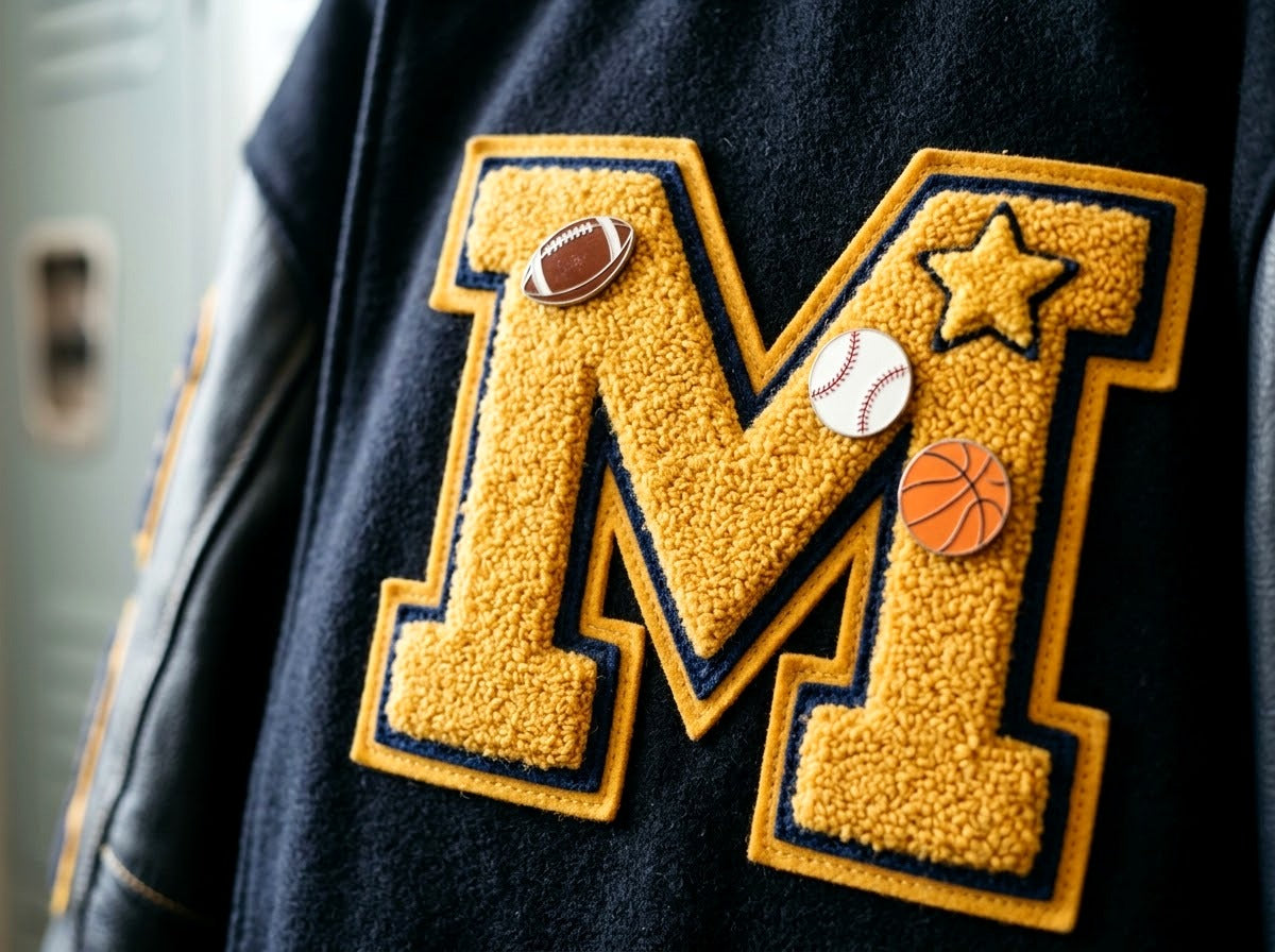 Lettre chenille d’une letterman jacket décorée de pins sportifs